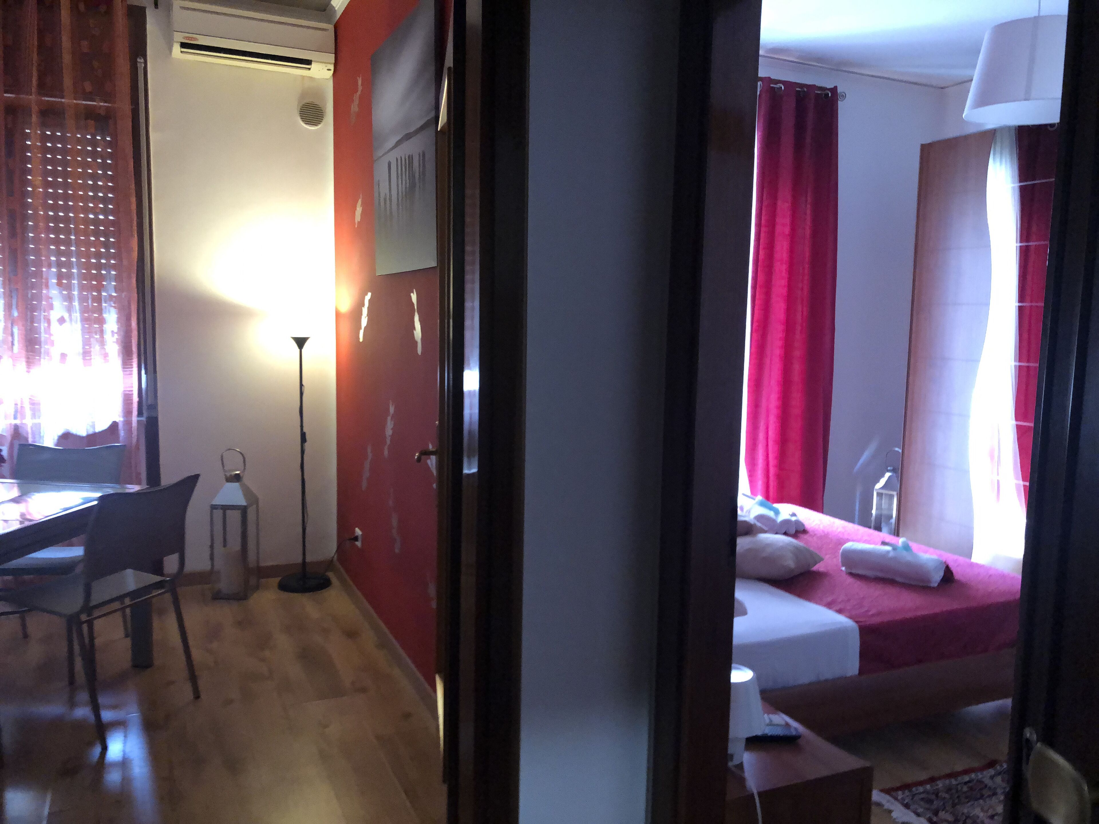 Ein Hotelzimmer mit Bett, Nachttisch, Lampe und Schreibtisch mit Stuhl.