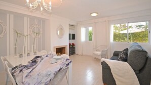 Amplia sala de estar con comedor, chimenea y un ventanal con vistas a la vegetación.