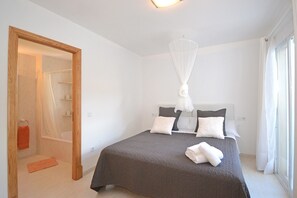 A bedroom with a bed, a shower, and a window.