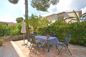 An outdoor patio with a round table, four chairs, and a small umbrella.
