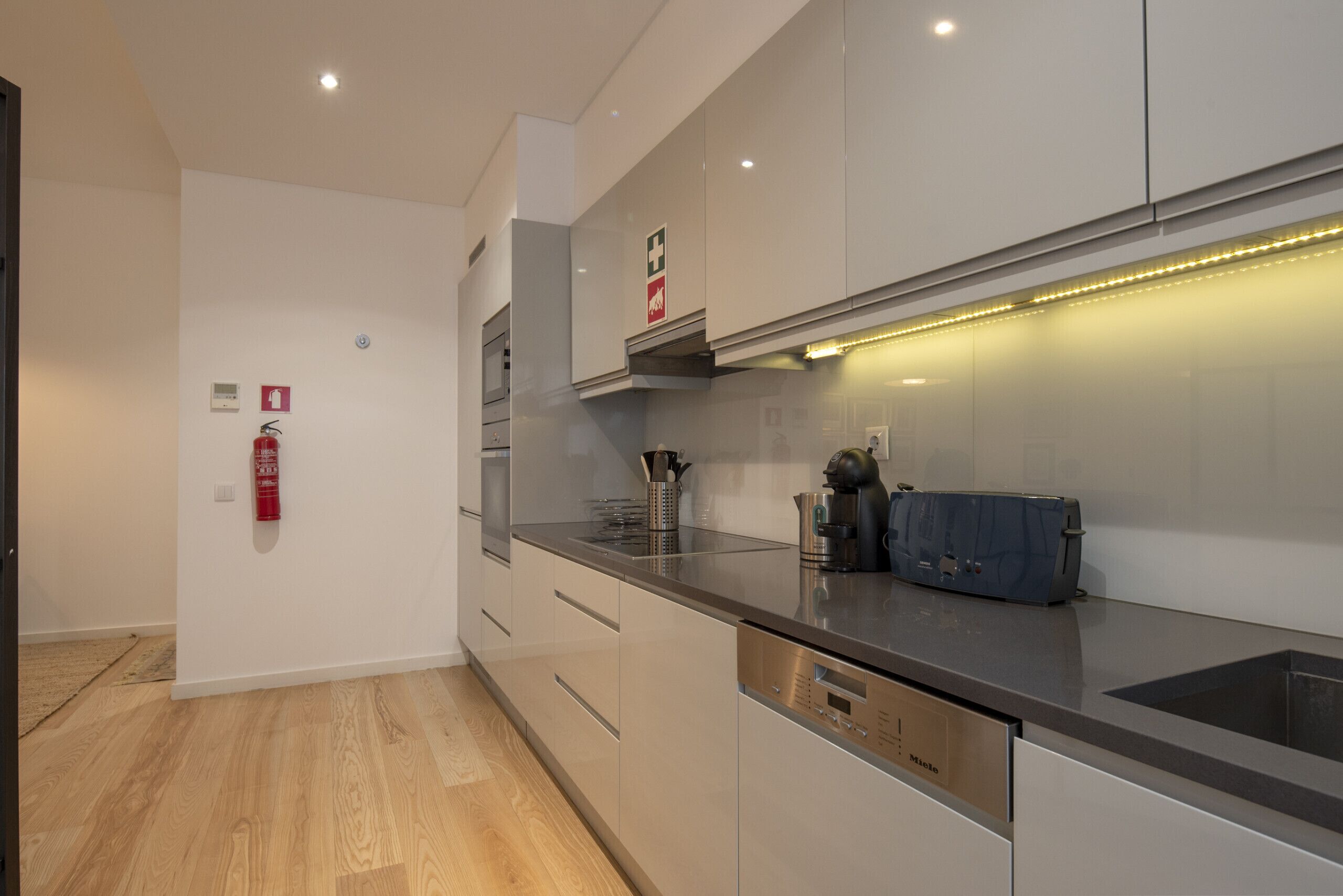 A modern kitchen with stainless steel appliances, a built-in oven, and a coffee machine.