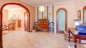 Una habitación amplia con zona de comedor, cómoda de madera y candelabro.