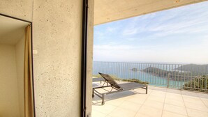 Een balkon met een metalen hekwerk, een metalen tafel en een metalen stoel.