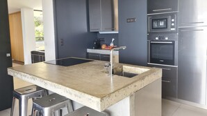 Een moderne keuken met een centraal eiland, roestvrijstalen apparatuur en een donkerblauwe accentmuur.