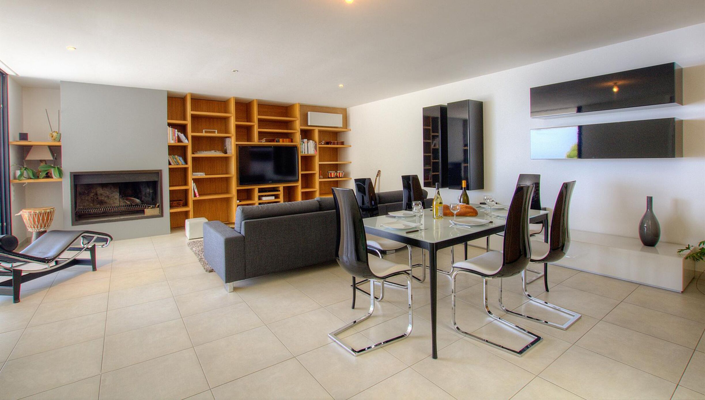 A modern living room with a dining area, a fireplace, and built-in shelves.