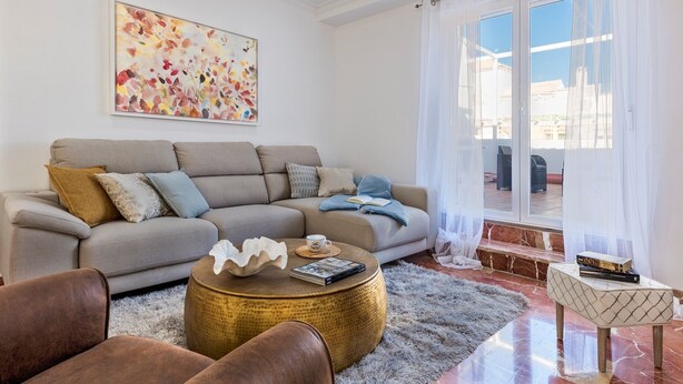 A living room with a beige sofa, a round coffee table, and a view of a terrace through a glass door. - Genteel Home Gran Capitan Terrace (Granada)