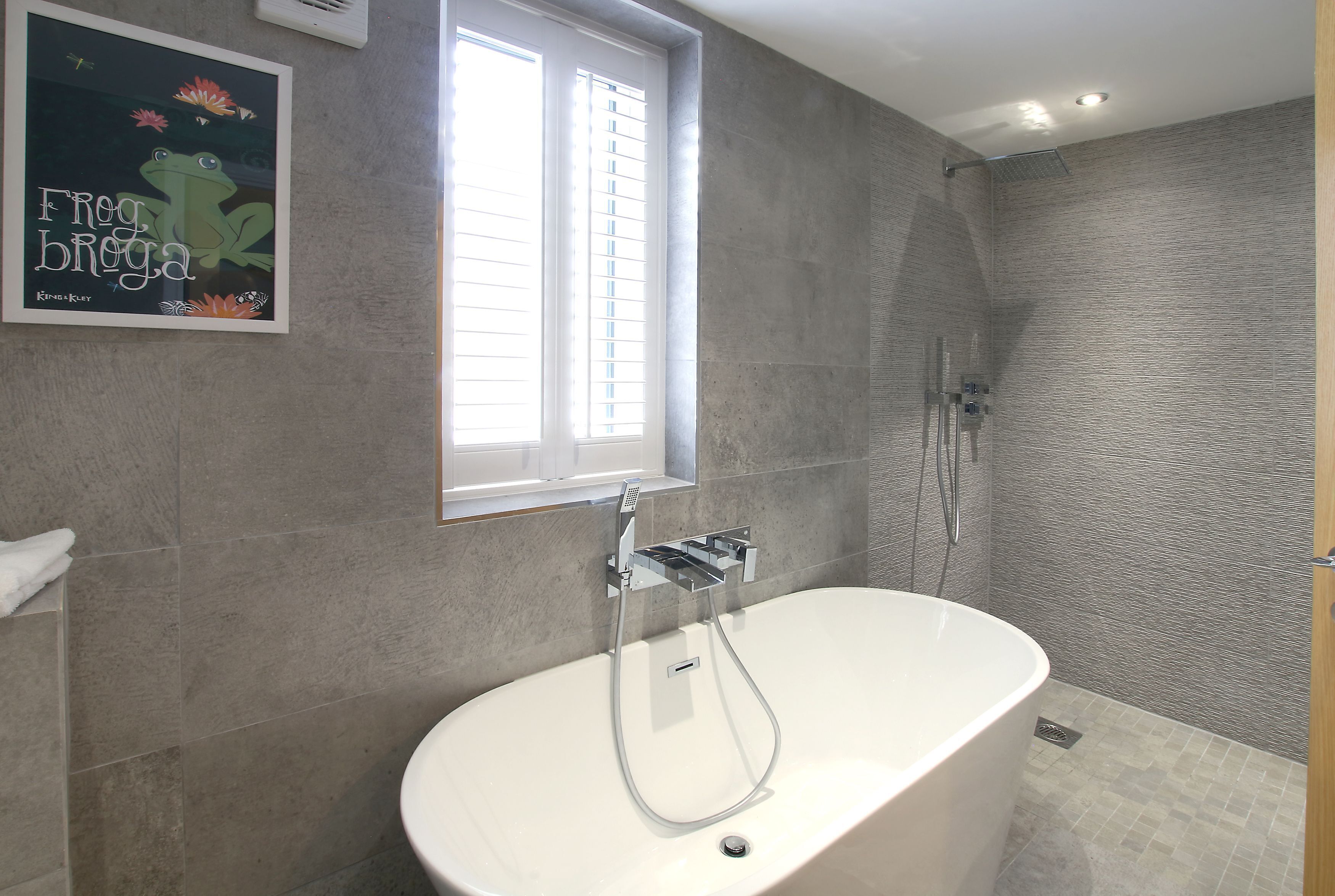 Un baño moderno con una bañera independiente, ducha y ventana que proporciona luz natural.