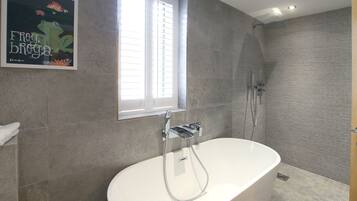Un baño moderno con una bañera independiente, ducha y ventana que proporciona luz natural.