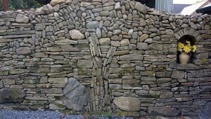 Un mur de pierre agrémenté d’une arche décorative et d’un vase rempli de fleurs.