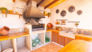 A kitchen with a built-in oven, shelves with kitchenware, and a tiled backsplash. - Can Roig 113 fantastic finca with private pool, garden, children's area and air-conditioning (Alcúdia)