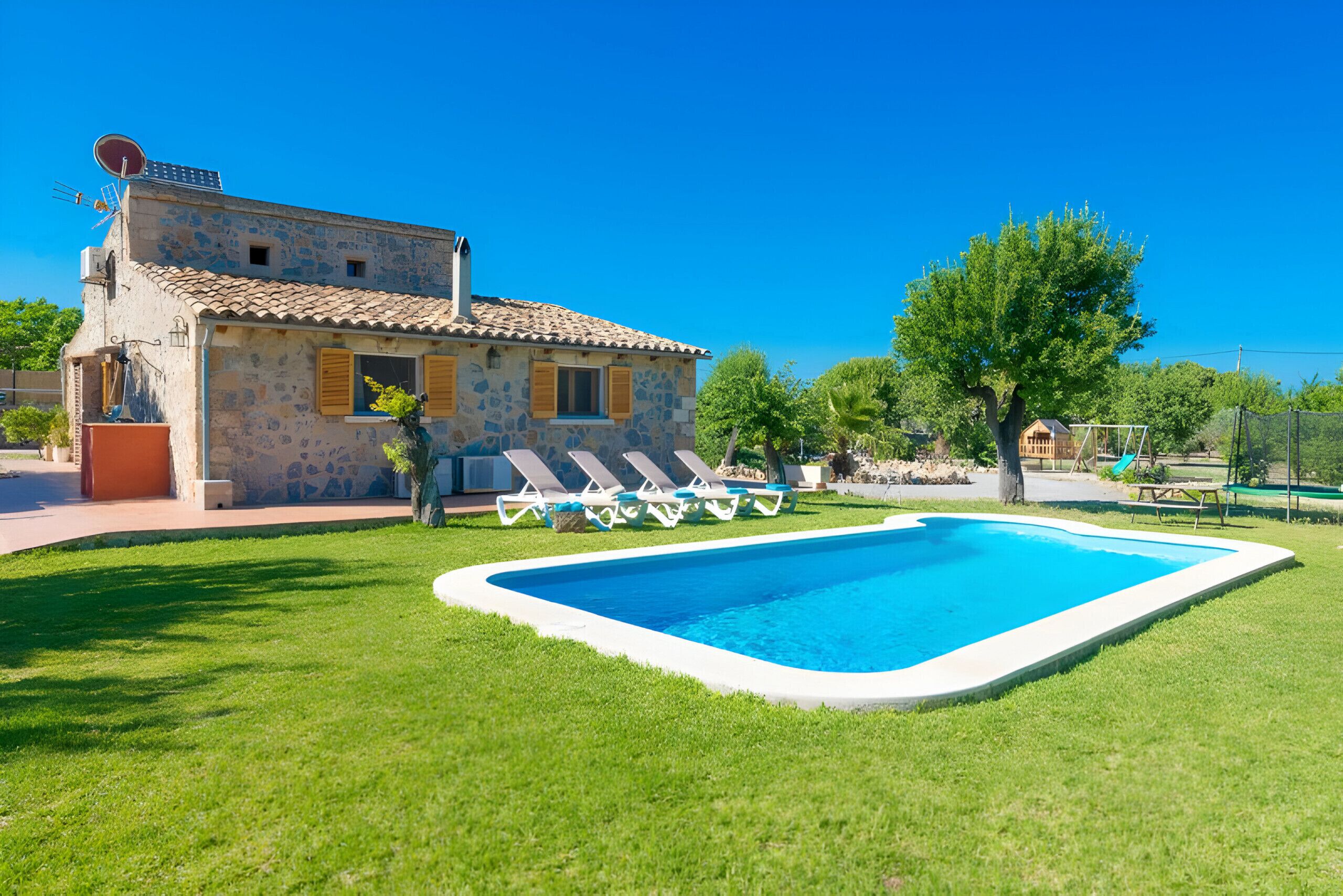 Une maison avec une piscine, un jardin et un arbre.