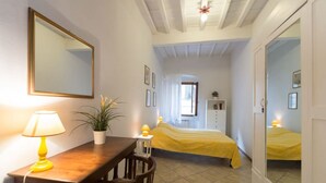 A bedroom with a bed, a bedside table with a lamp, a mirror, and a potted plant. - Castellani Apartment (Firenze)