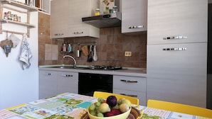 Una cocina moderna con estufa a gas, electrodomésticos de acero inoxidable y un comedor con una mesa lista para dos.