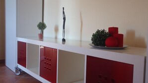 A white and red storage cart with a potted plant, a black sculpture, and red candles. - Ortigia, comfortable Baron house (Siracusa)
