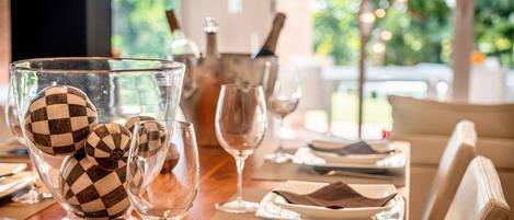 A dining table set with plates, glasses, and a bowl of decorative balls.