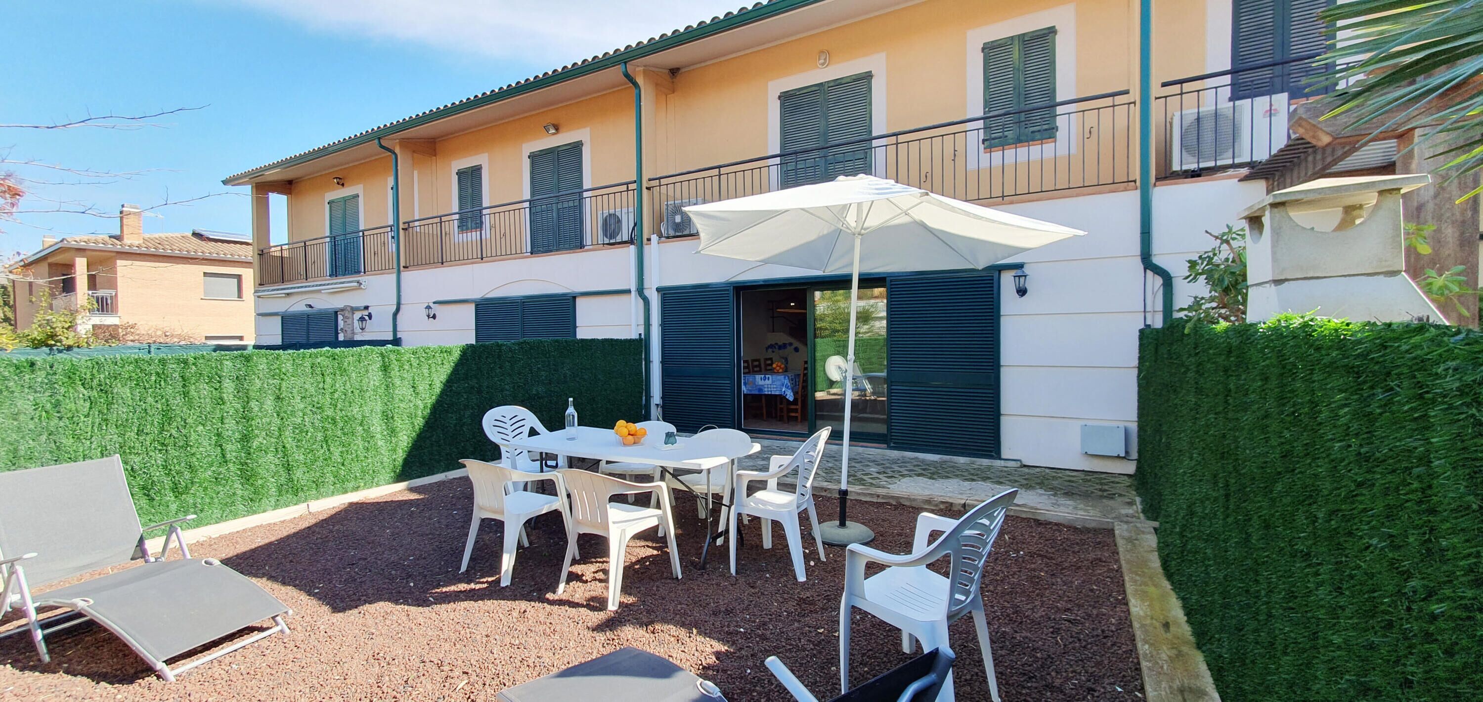 A villa with a patio area featuring a table, chairs, and an umbrella.