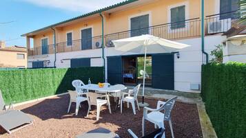 A villa with a patio area featuring a table, chairs, and an umbrella.