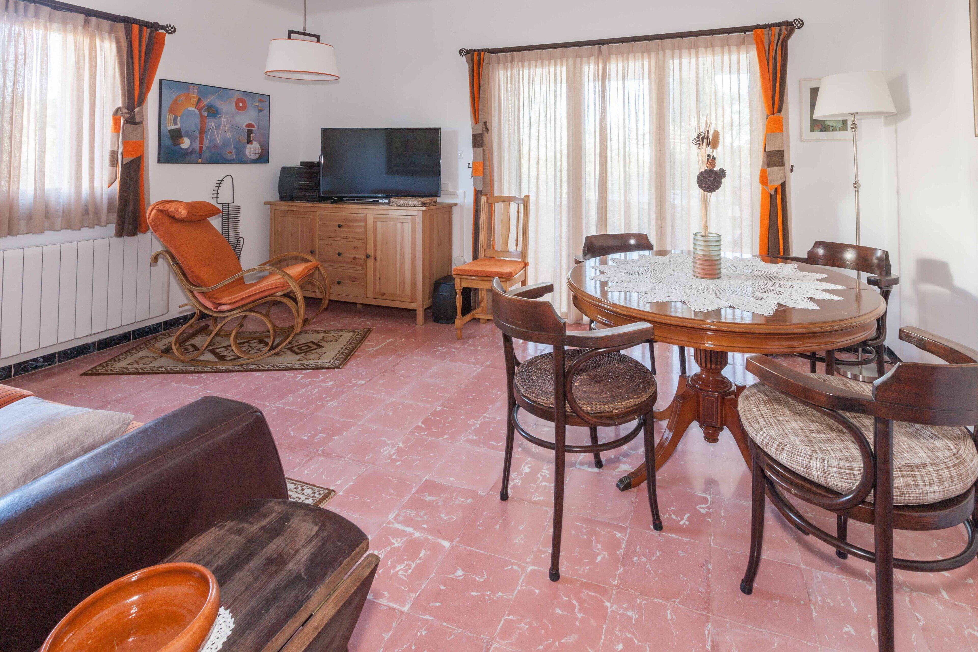 A dining area with a round table, chairs, a television, and a cabinet.