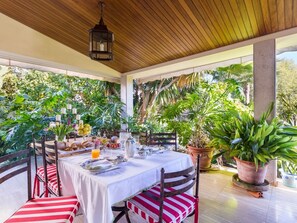 An outdoor dining area with a table set for two, surrounded by potted plants and a wooden ceiling. - Can Mandol - Spectacular luxury house with pool and large garden (Inca)