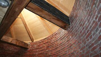 Un muro de ladrillo curvo con estructura de viga de madera y techo inclinado.