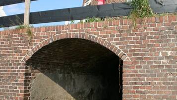 Een bogenbrug van baksteen met een houten looppad erboven.