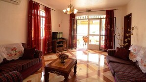 A living room with two sofas, a coffee table, a TV, and a door leading to an outdoor area. - Trou aux Biches - Rama Villas 4 (Trou aux biches)