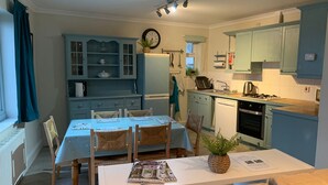 Une cuisine compacte comprenant une table à manger, des chaises et un petit îlot central.