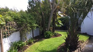 Un jardin bien entretenu, avec un chemin sinueux, une végétation luxuriante et un mur blanc.