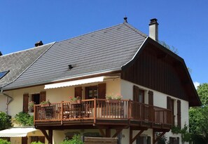 A two-story house with a balcony, wooden railings, and a chimney.