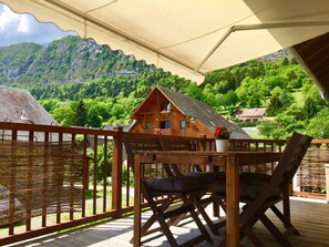 Eine Holzterrasse mit Tisch und Stühlen mit Blick auf eine gebirgige Landschaft.