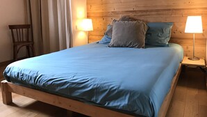 Ein hölzernes Bett mit blauer Bettdecke, zwei Nachttischlampen und einem Nachttisch.