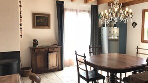 Ein Essbereich mit Holztisch, Stühlen, einer Kristallleuchtre und einem Kühlschrank.