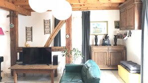 Ein Wohnzimmer mit Holzboden, einem Fernseher, einer Couch und einer Küchenzeile mit Schränken und Spüle.