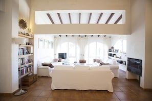 A spacious living room with a high ceiling, a fireplace, and a large sofa.