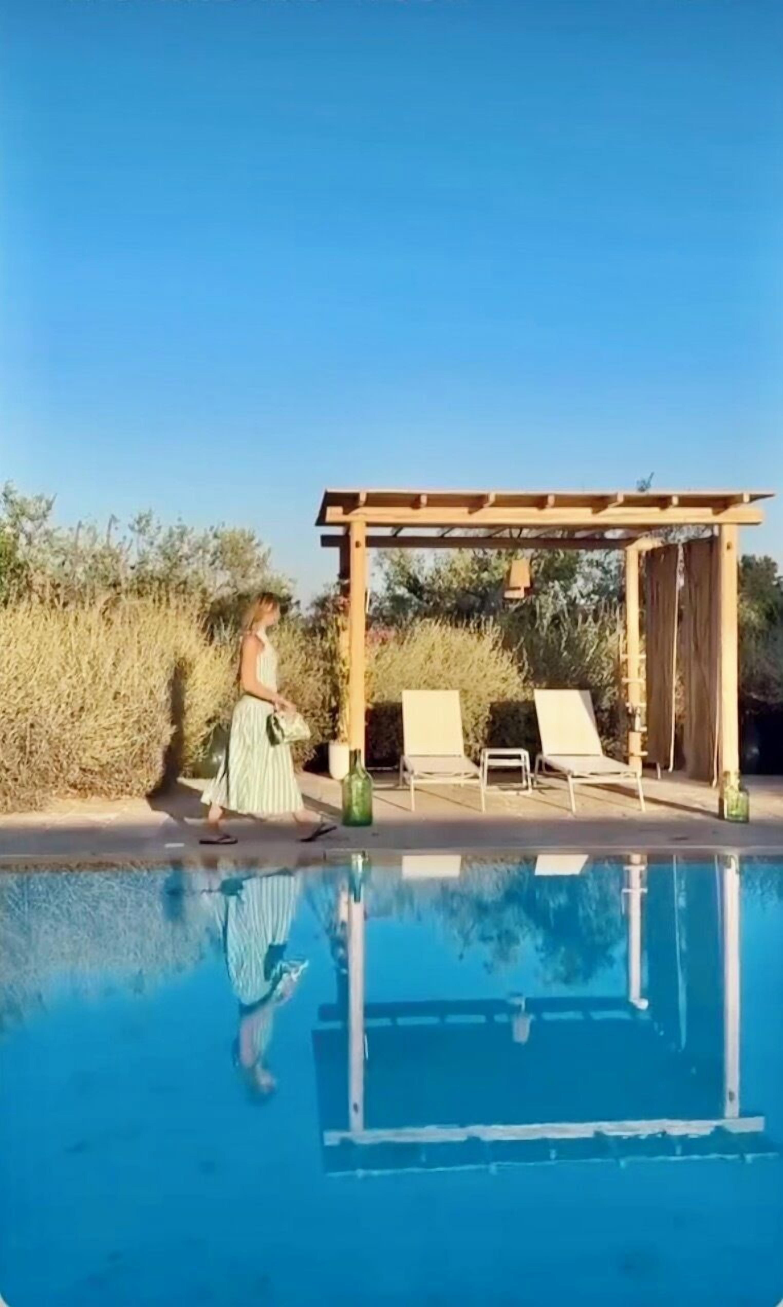 Ein Schwimmbecken mit Liegestühlen und einer Pergola.