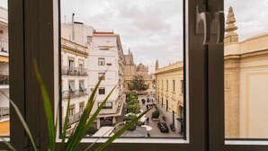 Une vue à travers une fenêtre donnant sur une rue bordée d’immeubles, dont un bâtiment remarquable surmonté d’un dôme.