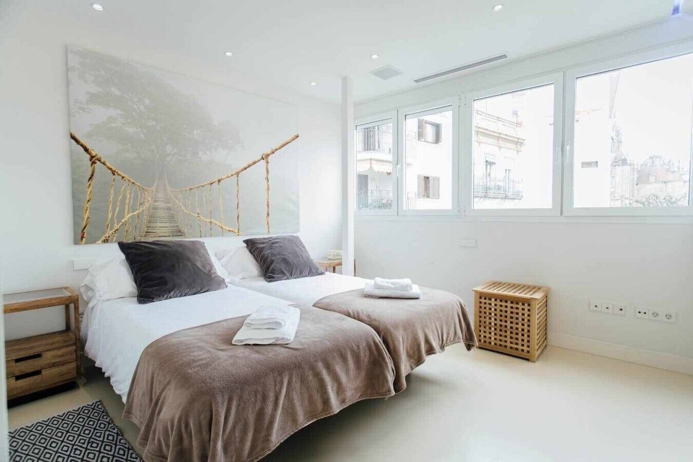 Ein modernes Schlafzimmer mit zwei Betten, einer Hängematte und Blick auf die Stadt.