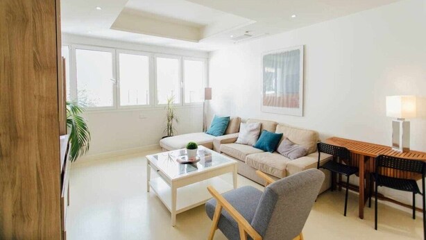 Un salon moderne comprenant un canapé, une table basse et un coin repas avec des chaises et une lampe.