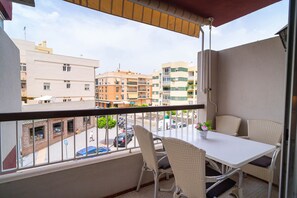 Un balcon agrémenté de meubles en osier, d’une table et d’une plante en pot.