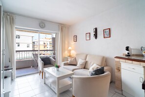 Una sala de estar moderna con un sofá, una mesa de centro y un comedor con una lámpara.