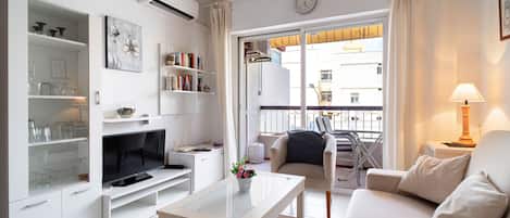 Een moderne woonkamer met een flatscreen televisie, een salontafel, een bank en een balkon met uitzicht op de stad.