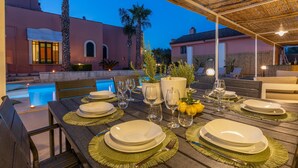 Un comedor con vista a la piscina, mobiliario exterior y un patio cubierto.