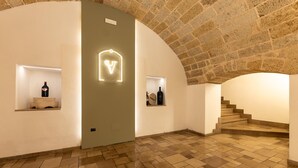 Un interior espacioso con techo abovedado de piedra, piso de baldosas y una escalera que conduce a un nivel superior.