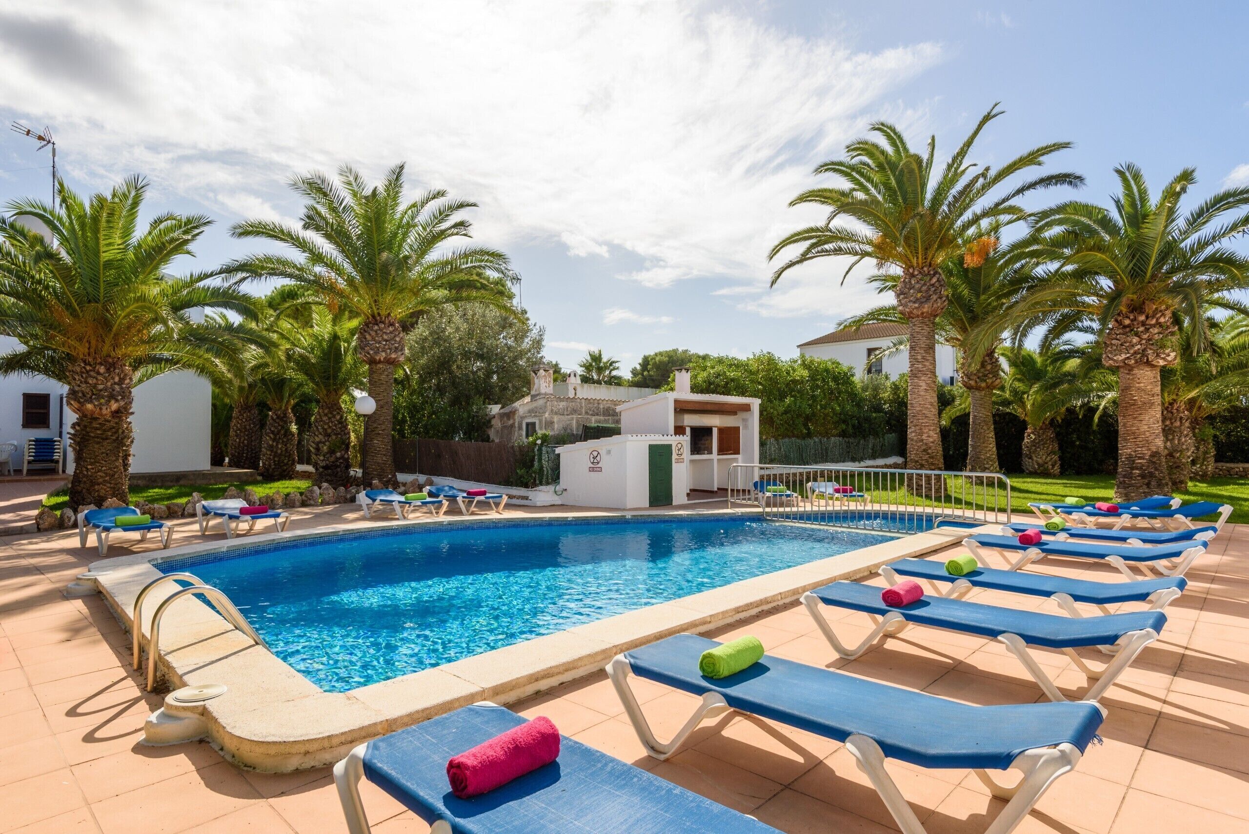 A swimming pool with lounge chairs and palm trees.