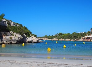 A coastal scene with clear blue water, rocky cliffs, and yellow buoys.