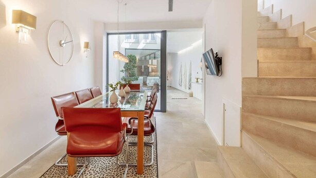 Un comedor moderno con una mesa de vidrio, sillas rojas y un tapete de estampado de leopardo.