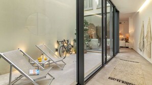 Ein modernes Interieur mit Glastür zu einem Balkon, einem Fahrrad und einer Sitzecke mit Kissen.