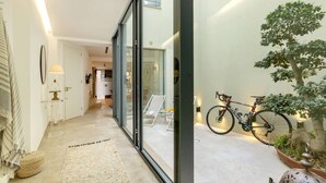 Ein modernes Interieur mit einem Flur, der zu einer Küche führt, einer Glastür und einem Fahrrad, das draußen abgestellt ist.