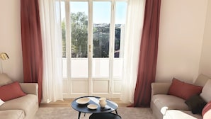 A living room with two sofas, a small round table with bowls, and a view through large windows.