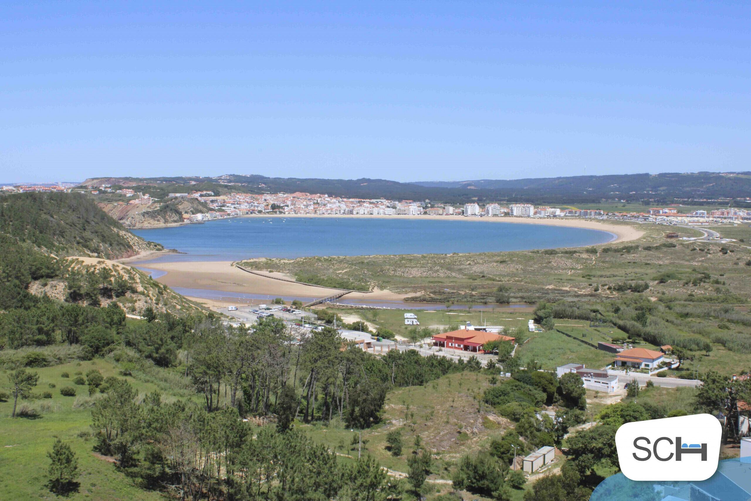 A coastal town with a beach, buildings, and greenery.
